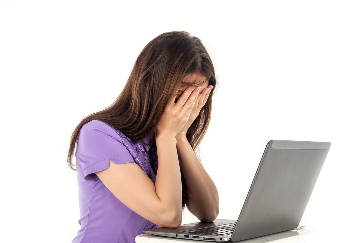Donna al computer con le mani sul volto